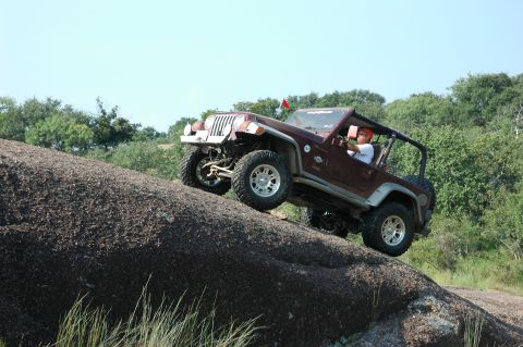 2001 Jeep Wrangler - 2001 Jeep Wrangler tackling an off-road obstacle on a sunny day.
