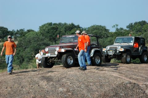2001 Jeep Wrangler - Several Jeep Wranglers are parked on a rocky landscape, with people milling about.