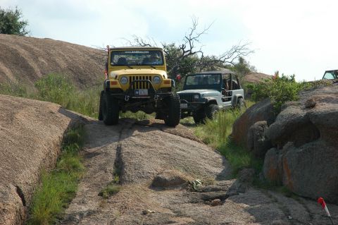 2001 Jeep Wrangler - Two Jeep Wranglers navigate a rocky terrain under a partly cloudy sky.