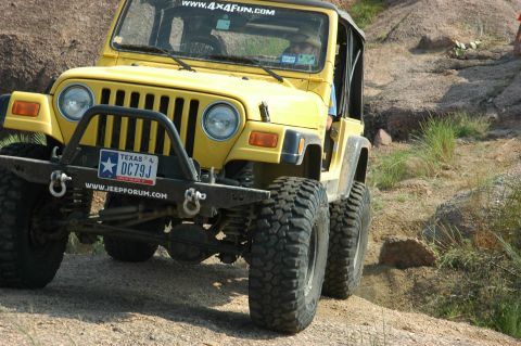 2001 Jeep Wrangler - This yellow 2001 Jeep Wrangler navigates a challenging off-road course with large, aggressive tires.