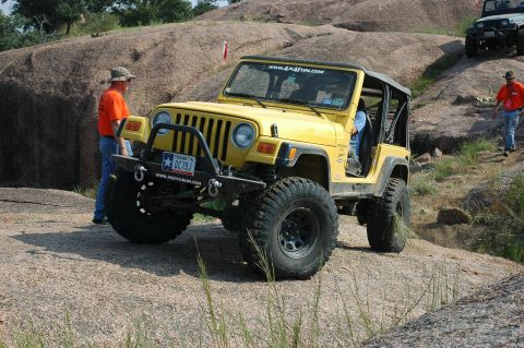 2001 Jeep Wrangler - Yellow 2001 Jeep Wrangler navigating a rocky off-road course with another Jeep visible in the background.