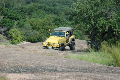 2001 Jeep Wrangler - A yellow 2001 Jeep Wrangler navigates a challenging rocky path, demonstrating its off-road capabilities.