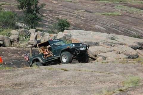 2001 Jeep Wrangler - A Jeep Wrangler navigates a rocky, off-road terrain with a driver and passenger inside.