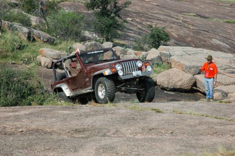 2001 Jeep Wrangler - A maroon Jeep Wrangler navigates a rocky landscape, demonstrating its off-road capabilities.