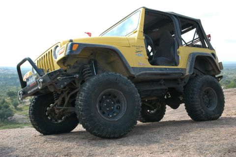 2001 Jeep Wrangler - A yellow 2001 Jeep Wrangler is shown off-road, large tires and a modified bumper.
