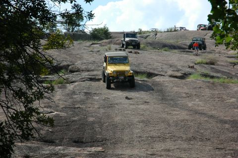 2001 Jeep Wrangler - Multiple Jeep Wranglers navigate a challenging rocky terrain under a partly cloudy sky.