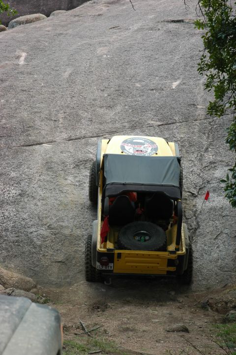 2001 Jeep Wrangler - A yellow Jeep Wrangler navigates a steep rock incline, its off-road capabilities.