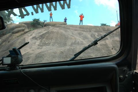 2001 Jeep Wrangler - Three people stand on a large rock formation, viewed from inside a vehicle.