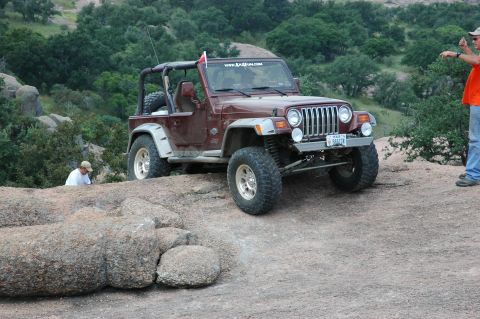2001 Jeep Wrangler - 2001 Jeep Wrangler navigating rocky off-road terrain with a person observing.