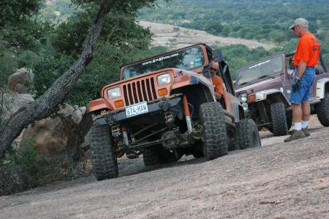2001 Jeep Wrangler - Two Jeeps navigate a rocky, off-road trail with a wooded hillside in the background.