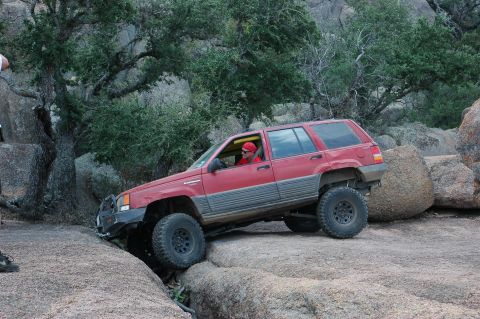 2001 Jeep Wrangler - Red Jeep Grand Cherokee tackling a challenging off-road course with large boulders.