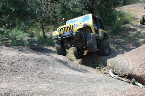 2001 Jeep Wrangler - A yellow 2001 Jeep Wrangler navigates a challenging rocky terrain with another vehicle visible in the background.