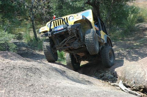 2001 Jeep Wrangler - A yellow 2001 Jeep Wrangler navigates a challenging rocky off-road course.