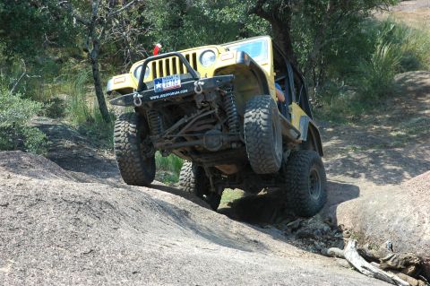 2001 Jeep Wrangler - Yellow 2001 Jeep Wrangler navigating rough terrain on a rocky hill.