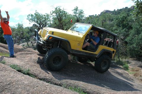 2001 Jeep Wrangler - A yellow 2001 Jeep Wrangler navigates a challenging rocky incline, with a person cheering from the side.