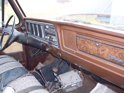1978 Ford F-250 - The interior of an older truck shows a dashboard with woodgrain accents and a "RANGER" emblem, along with an exposed aftermarket radio unit.