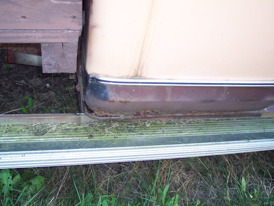 Truck lower body panel with rust and chrome trim, viewed from the side