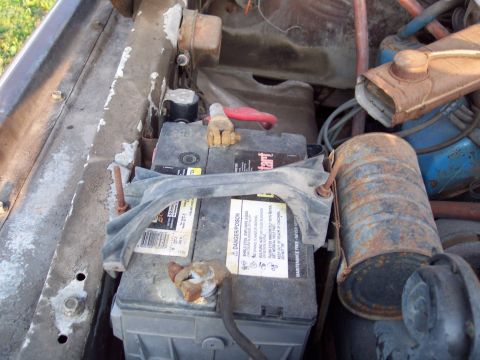 1978 Ford F-250 - The engine compartment of a vehicle, a battery and various engine parts.