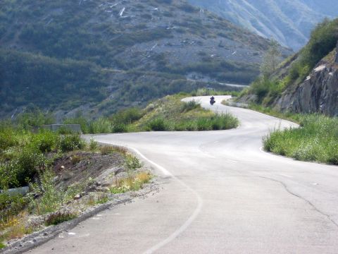 1979 Ford Bronco - A motorcycle rides on a winding road through a mountainous landscape.