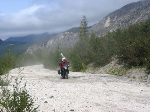 1979 Ford Bronco - A lone rider navigates a remote, dusty road through a mountainous, wooded landscape.
