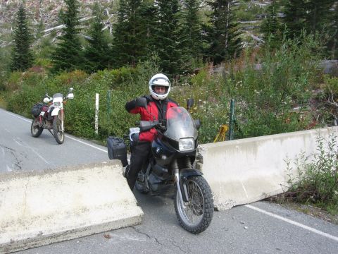 1979 Ford Bronco - Two motorcycles are stopped on a road due to a concrete barrier blocking the path.