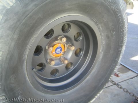 1990 Ford Bronco - Close-up of a gray off-road truck wheel on a BFGoodrich tire with a blue ATX-branded center cap, on a trailer deck.