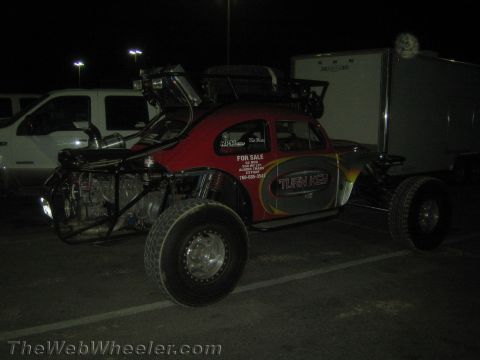 1990 Ford Bronco - red Volkswagen Beetle-bodied off-road race buggy marked Turn Key and For Sale sits in a parking lot at night beside a box trailer.