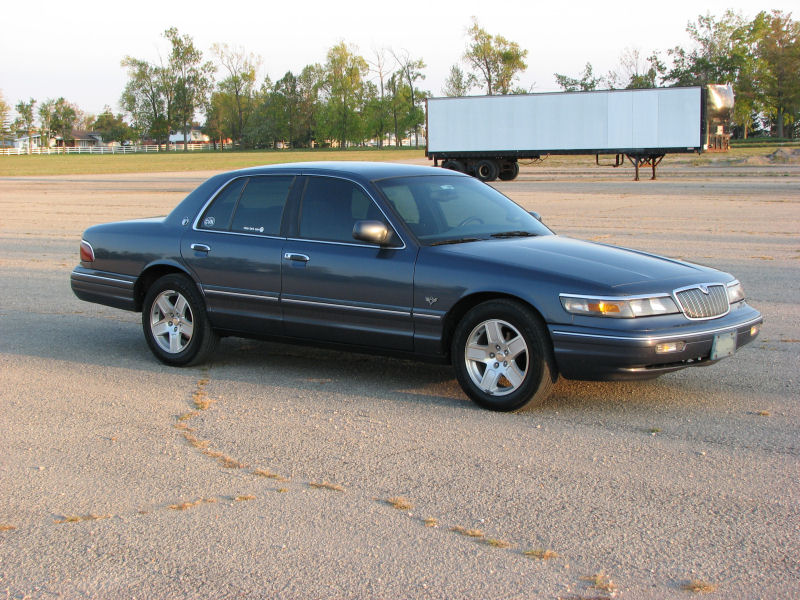 Dark blue sedan, 3/4 front view. Later model Mercury Grand Marquis