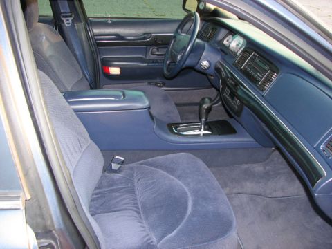 1985 Mercury Grand Marquis - The interior of a blue sedan features plush cloth seats and a clean dashboard with an automatic transmission shifter.