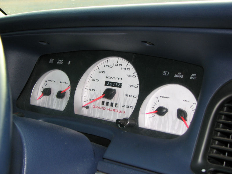 Dashboard gauges with 'GRAND MARQUIS' text, showing 26372 miles, speedometer, fuel, volts, temperature, and oil gauges