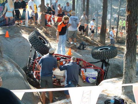 2002 Jeep Wrangler - An off-road vehicle is stuck on a steep, rocky terrain during an event, with spectators observing the situation.
