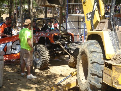 2002 Jeep Wrangler - An off-road buggy is being pulled by a large yellow construction vehicle at an outdoor event.