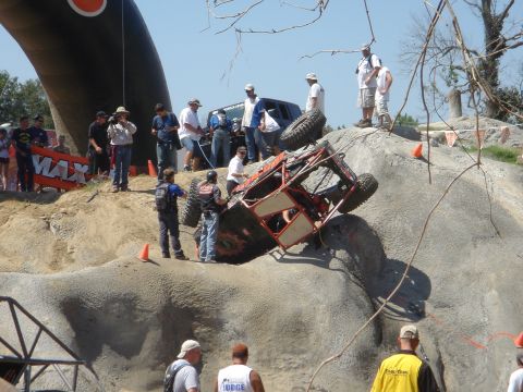 2002 Jeep Wrangler - A custom-built rock crawler is overturned on a challenging course, with onlookers observing the event.