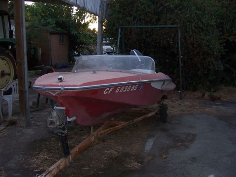 1991 Ford Bronco - A red boat sits on a trailer in an outdoor setting.