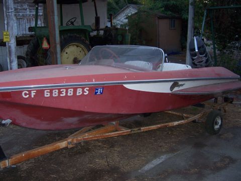 1991 Ford Bronco - A red boat with white trim and registration numbers is parked on a trailer.