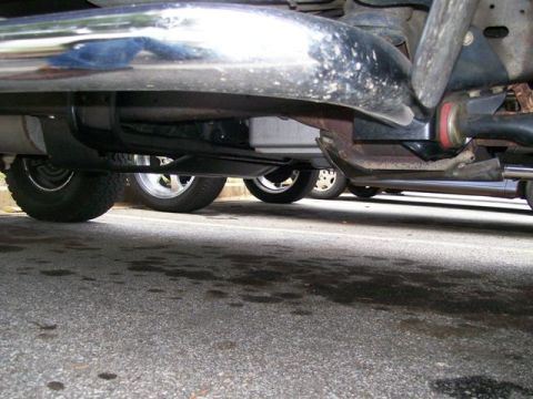 1990 Ford Bronco - Undercarriage view shows suspension and exhaust system components of a vehicle parked on asphalt.