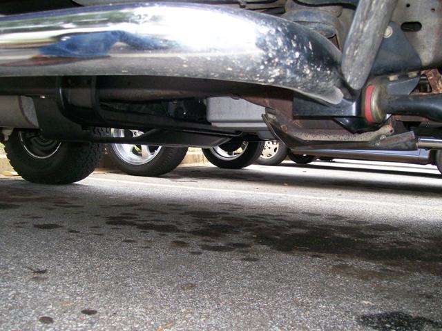 Undercarriage view of a vehicle with chrome exhaust pipe and suspension components