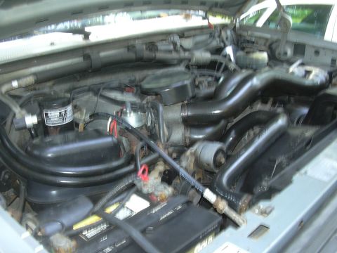 1997 Ford Crown Victoria - Close-up view of a vehicle's engine bay, showing various hoses and the battery.