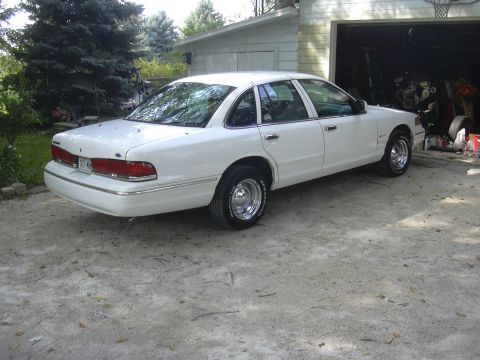 1997 Ford Crown Victoria - A white 1997 Ford Crown Victoria is parked outside a garage with its rear facing the camera.