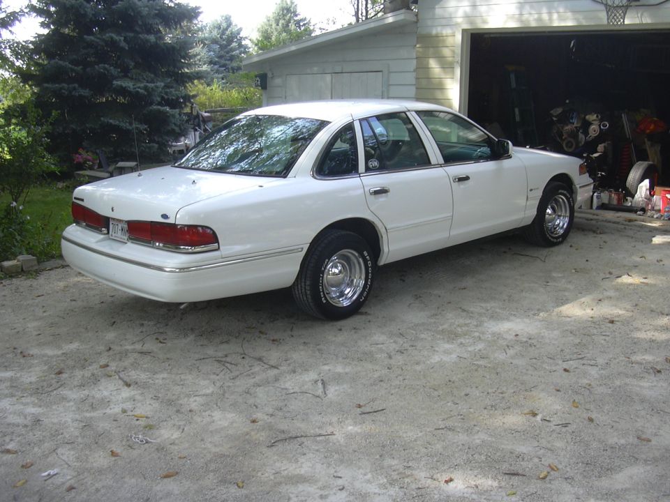 White 1997 Ford Crown Victoria parked in a driveway next to an open garage