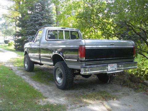 1997 Ford Crown Victoria - This 1987 Ford F-150 pickup truck features a two-tone paint scheme and lifted suspension, viewed from the rear.