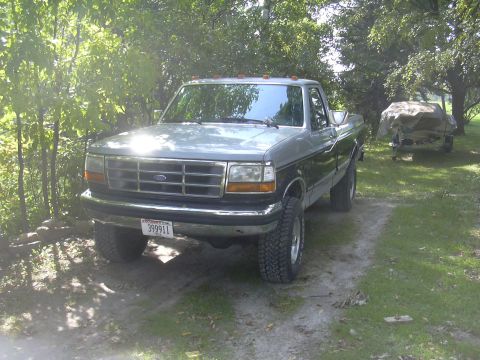 1997 Ford Crown Victoria - This two-tone Ford F-Series pickup truck, likely from the mid-1990s, is parked outdoors on a dirt path.