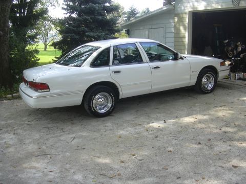1997 Ford Crown Victoria - A white 1997 Ford Crown Victoria is parked in a driveway next to an open garage.