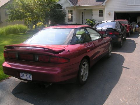 1996 Ford Probe - Rear view of a red 1996 Ford Probe, parked in a driveway with other vehicles.