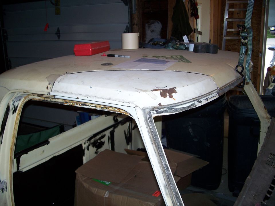 White 1979 Ford F-150 cab roof with rust spots, viewed from a 3/4 front angle inside a garage