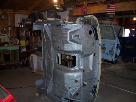 1979 Ford F-150 - The underside of a vehicle frame is shown upside down in a workshop, with another vehicle visible in the background.