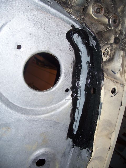 1979 Ford F-150 - A section of a vehicle's chassis shows repair work with black sealant applied to the metal.