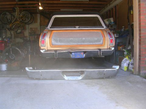 1975 Ford Ranchero - The rear of a 1975 Ford Ranchero is shown in a garage with its bumper detached and resting on the floor.