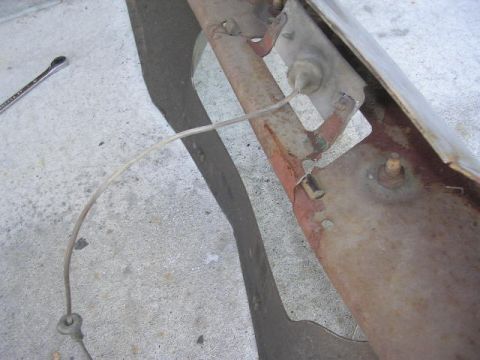 1975 Ford Ranchero - Close-up view of a rusted bumper section with a wire and a wrench on a concrete surface.