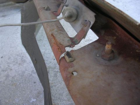 1975 Ford Ranchero - Close-up of a rusted metal bracket with a bolt and wire, likely from a vehicle's undercarriage.